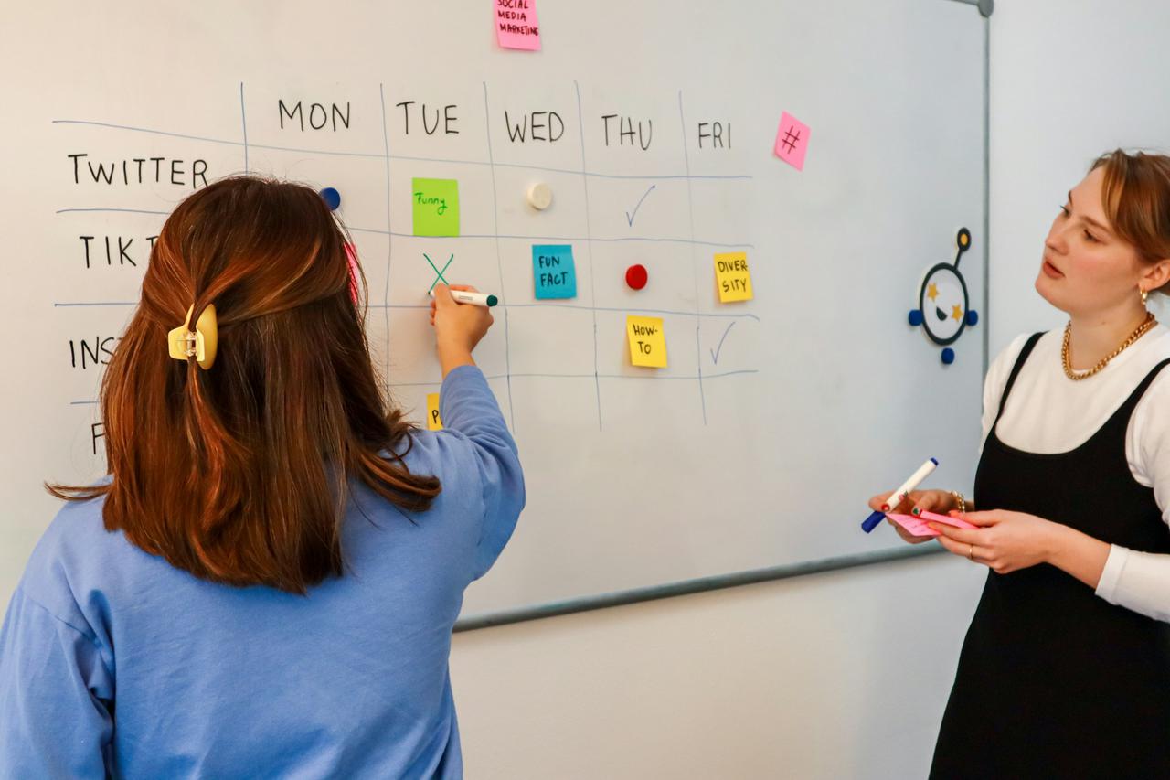 Marketing team planning weekly content for social media in front of a white board